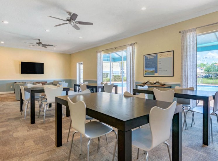 Clubhouse with Large Windows Black Tables with White Chairs Mounted TV and Ceiling Fans